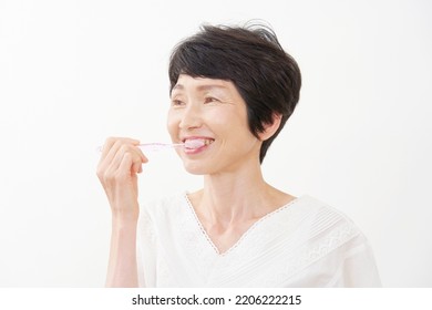 Asian Middle Aged Woman Brushing Her Teeth In White Background