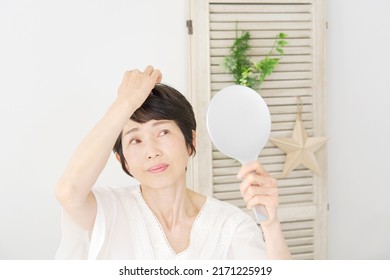 Asian Middle Aged Woman Checking Her Hair Withe Mirror At Home