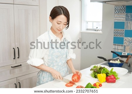 Asian middle aged woman cutting vegetables at the kitchen