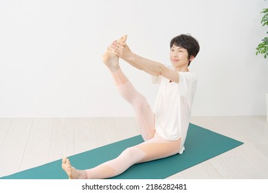 Asian Middle Aged Woman Doing Yoga At Home