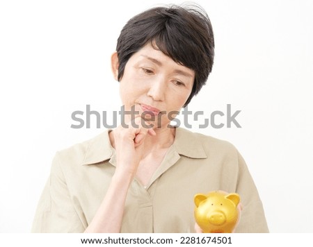 Asian middle aged woman having trouble with the piggy bank in white background