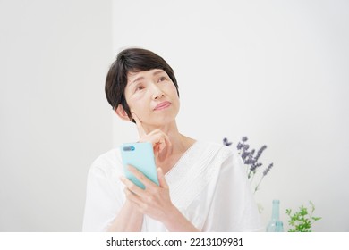Asian middle aged woman using the smartphone at home