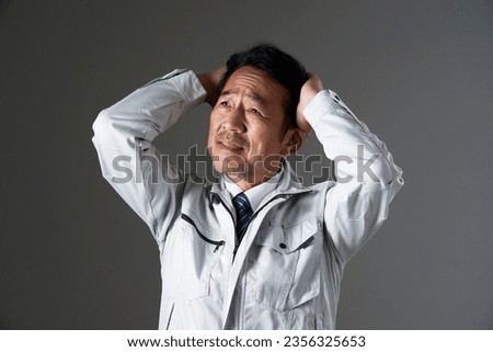 Asian middle aged worker holding his head in black background