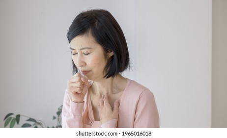 Asian middle woman coughing at home - Powered by Shutterstock