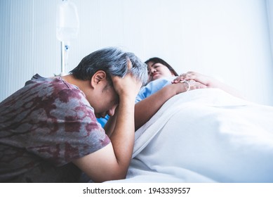 Asian middle-aged husband Stressed and upset by his wife's illness Lying in a patient's bed, she has diabetes and heart disease, caused by obesity, to relationship family and health care concept.