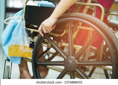 Asian middle-aged lady woman patient sitting on wheelchair with urine bag in the hospital ward : healthy medical concept               