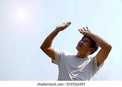 Asian middle-aged man feels hot, stands outdoor in sunny day. Concept : hot weather in summer, high temperature. Global warming. Heat wave. Uncomfortable feeling.      