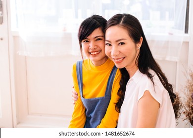 Asian middle-aged mother and teenage daughter smiling happily and looking at camera in indoors living room environment - with copy space - Shutterstock ID 1481652674