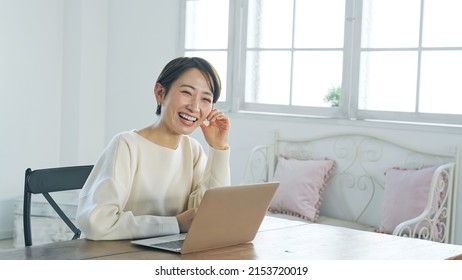 Asian middle-aged woman smiling while using a laptop PC. - Shutterstock ID 2153720019