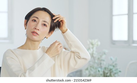 Asian Middle-aged Woman Styling Hair.