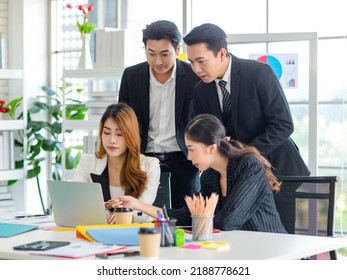 Asian Millennial Professional Successful Male Businessman Mentor In Black Formal Suit Standing Helping Two Female Employee Sitting Working With Laptop Computer At Workstation In Company Meeting Room.