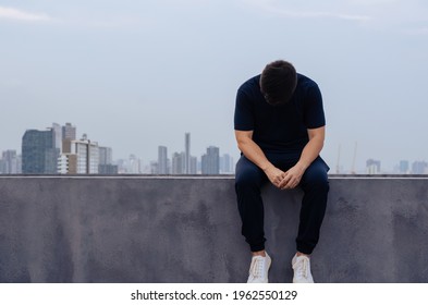Asian miserable depressed man sit alone with city background. Depression and mental health concept.