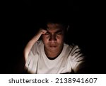 Asian miserable depressed man sitting alone in dark background. Depression and mental health concept.