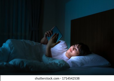 Asian mobile addict woman using digital tablet browsing the internet for watching movie or virtual meeting video call online with boyfriend on the bed before she sleeping at night.
 - Powered by Shutterstock