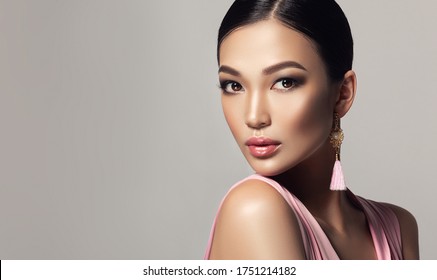 Asian Model  Fashion Girl  With Tassel Earrings And  Pink Dress . Cosmetology, Beauty And Clothing