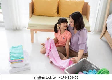 Asian Mom And Daughter Fold Cloth Doing Laundry Together At Home