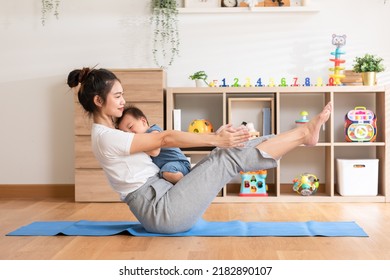 Asian Mom Doing Yoga Exercise Balance Body With Adorable Infant Baby On Yoga Mat Smiling And Happiness At Home. Relax Time. Baby And Mother Day