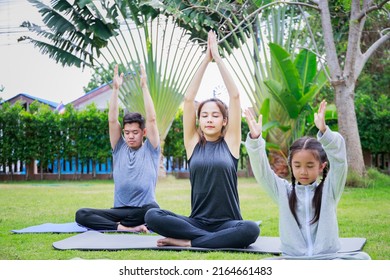 Asian Mom And Girl Training Yoga Child Daughter On A Yoga Mat At Home Garden.