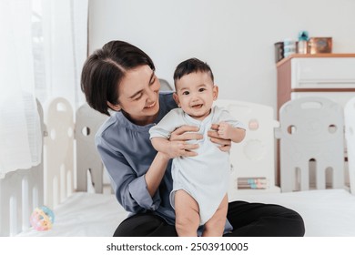 Asian mom lifting and playing newborn baby. Happiness Asian mother conference and playing with adorable her son looking at camera. Happy asian family healthcare love together mother day concept.