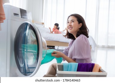 Asian Mom Loading Cloth To Washing Machine Doing Laundry At Home