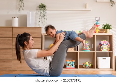 Asian Mom Playing To Adorable Infant Baby On Yoga Mat Smiling And Happiness At Home. Mom Talking With Baby Fun And Laughing Throwing Up Son In The Air Exercise Together. Relax Time. Baby And Mother Day