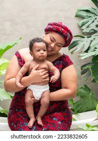 Asian mom wearing red african costume holding multiracial, Thai African son. Adorable baby boy making funny face. Love and bonding mother and child concept. - Shutterstock ID 2233832605