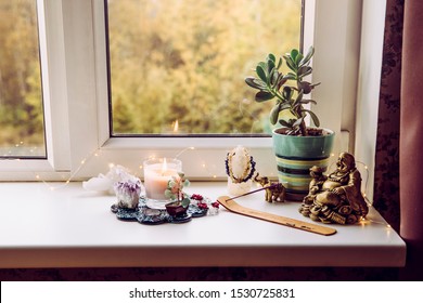 Asian money tree Crassula Ovata growing on window sill in home Feng Shui wealth and prosperity invitation altar. With smoking incense stick, laughing Buddha and crystal clusters.