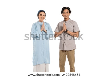 Asian moslem couple greeting gesture for ramadan eid mubarak. Smile looking at camera wearing Ramadan theme clothes, in white background.