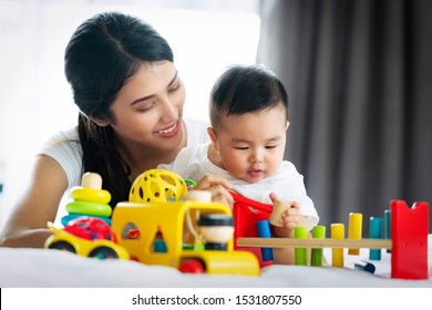 Asian Mother And Baby Play Togather With Wooded Toy In Bed Room, This Image Can Use For Boy, Mom, Study, Education And Mother's Day Concept