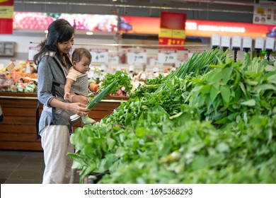 Asian Mother And Baby Shopping In The Supermarket. Grocery Store Shopping