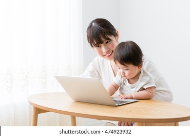 Asian Mother And Baby Using Laptop In The Living Room