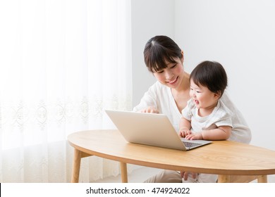 Asian Mother And Baby Using Laptop In The Living Room