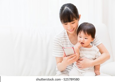 Asian Mother And Baby Using Smart Phone 