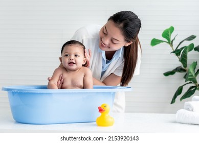 Asian mother Bathing her 7 month old daughter, which the baby smiling and happy, with white background,  to Asian family and baby shower concept.