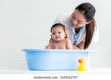 Asian mother Bathing her 7 month old daughter, which the baby smiling and happy, with white background,  to Asian family and baby shower concept. - Powered by Shutterstock