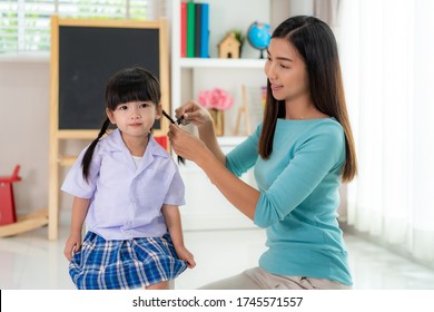 Asian mother Braiding her daughters hair sitting on chair, smiling single mom sister helping child girl with hairstyle at home getting ready to school, family care, morning preparations lifestyle.
 - Powered by Shutterstock