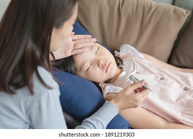 Asian Mother Checking Her Kid Body Temperature By Thermometer Which Got Fever And Illness At Home.