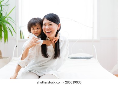 Asian Mother And Child Relaxing On The Bed Room