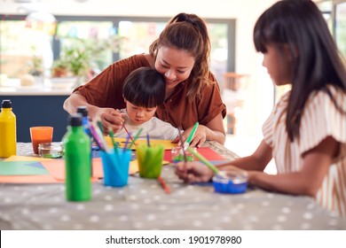 Asian Mother With Children Having Fun With Children Doing Craft On Table At Home