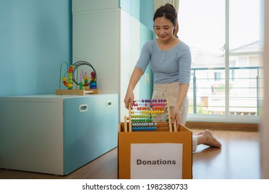 Asian Mother Are Choosing Their Children's Toys That Are Not Playing And Putting Donation Boxes To The Donation Center.
