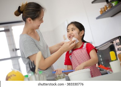 Asian Mother Cleaning Her Daughter Face In Cooking Time