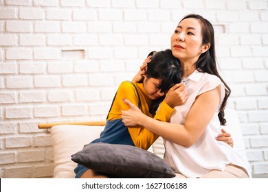 Asian Mother Comforting Crying Teenage Daughter In Miserable, Stressed, Depressed, Sad State Of Mind. 40s Mom Is Hugging This Adolescent Teenager Shoulders At Indoors Room.