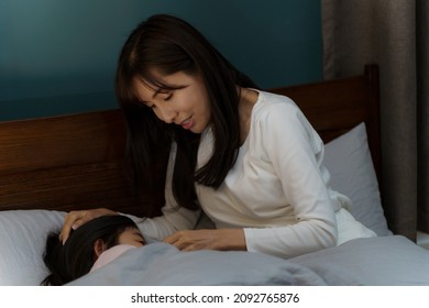 Asian Mother And Daughter Getting Ready For Sleep In Bed