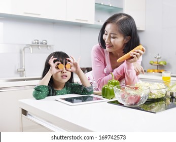 Asian Mother And Daughter Having Fun In Kitchen.