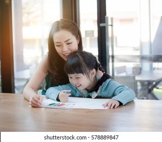 Asian Mother And Daughter Are Having Fun While Drawing At Home.mother And Her Child Colors Together