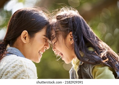 asian mother and daughter having a good time outdoors in city park - Powered by Shutterstock