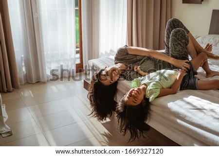 asian mother and daughter lying on the bed when enjoy playing together