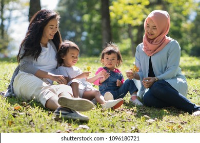 Asian Mother And Daughter Playdate With Friends In The Park Together