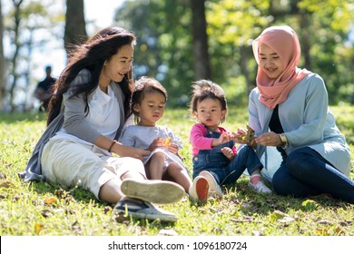 Asian Mother And Daughter Playdate With Friends In The Park Together