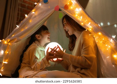 Asian Mother and daughter relax with tent and light in they bed room and read a teblet togather on night time at home - Powered by Shutterstock